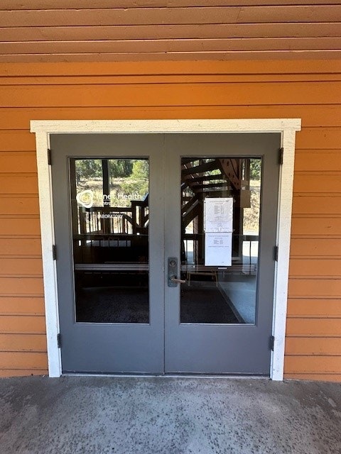Double glass doors on an orange building with papers posted, reflecting trees and a structure outside.