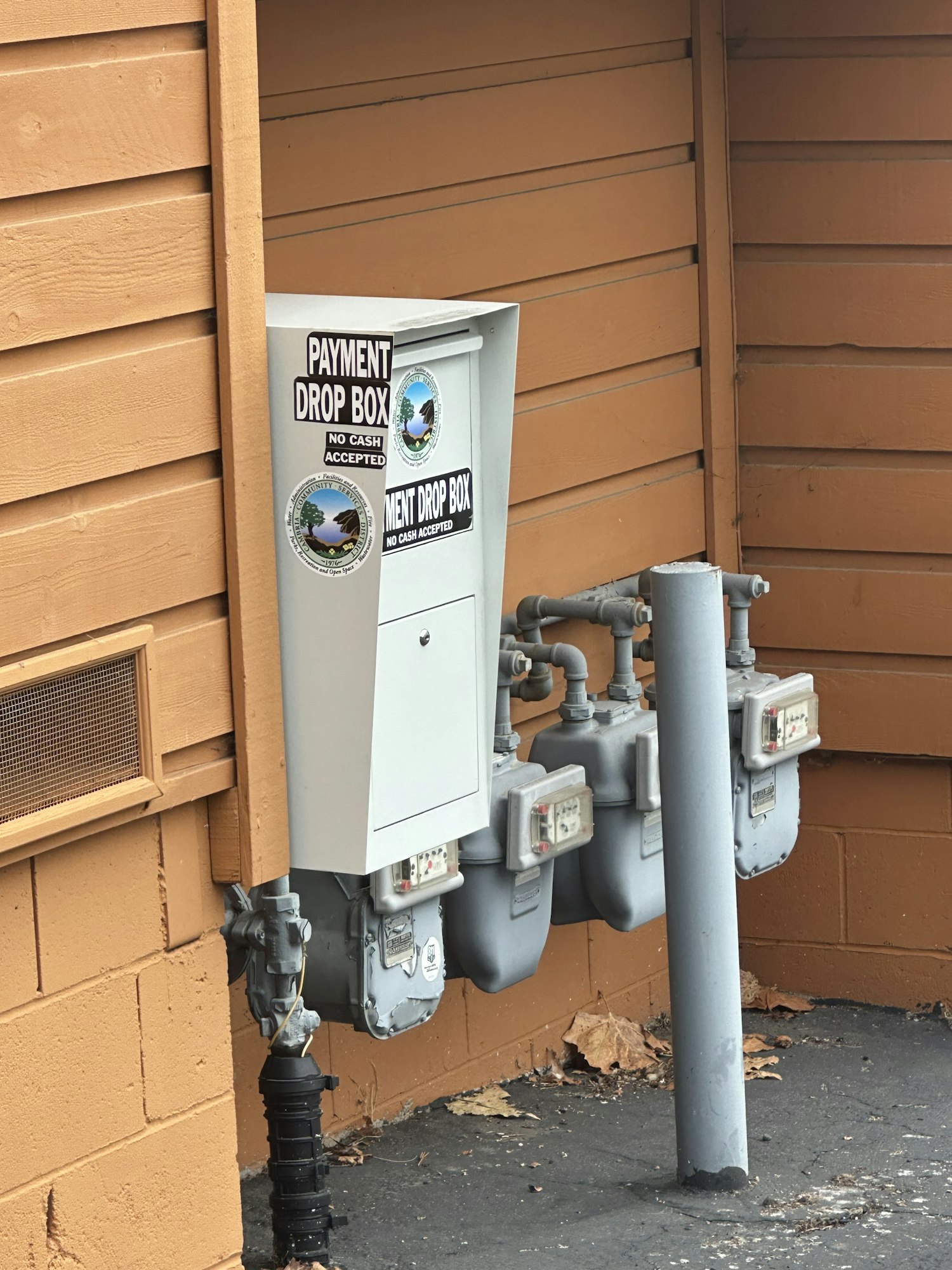 Payment drop box labeled "No Cash Accepted," next to utility meters.
