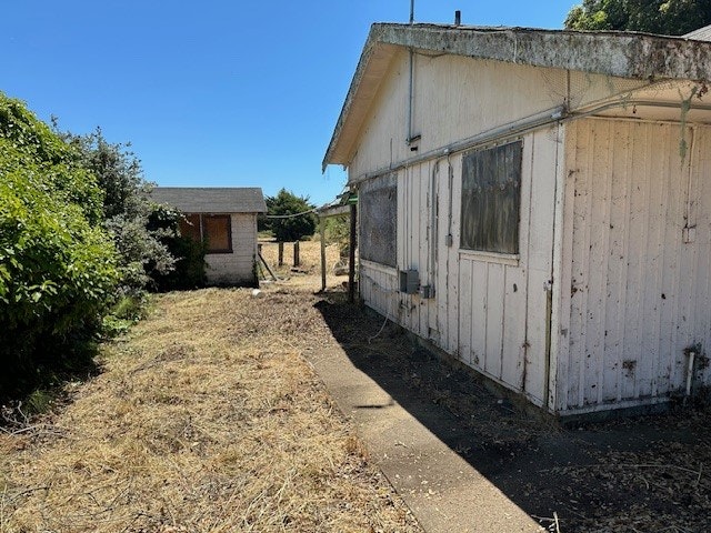 A dilapidated building with overgrown grass and a clear sky.