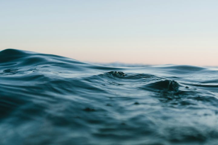 Ocean waves under a calm sky at sunset, capturing a peaceful seascape.