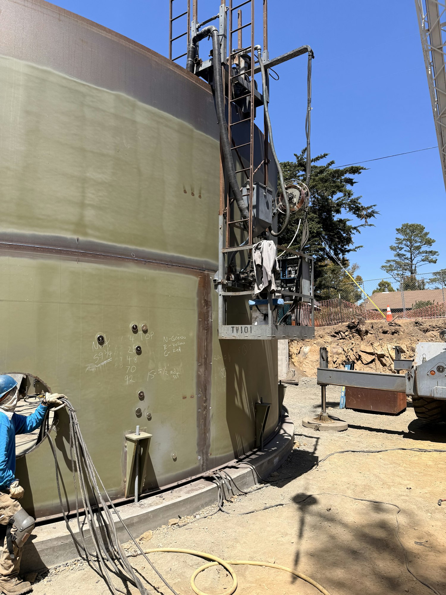The image shows industrial equipment, likely a storage tank, with construction tools and a worksite background.