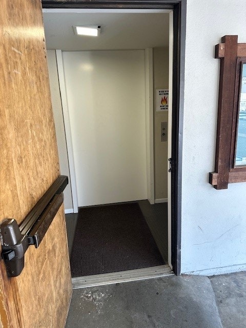 Open door showing an interior entrance with a brown mat and a cross on the right wall.