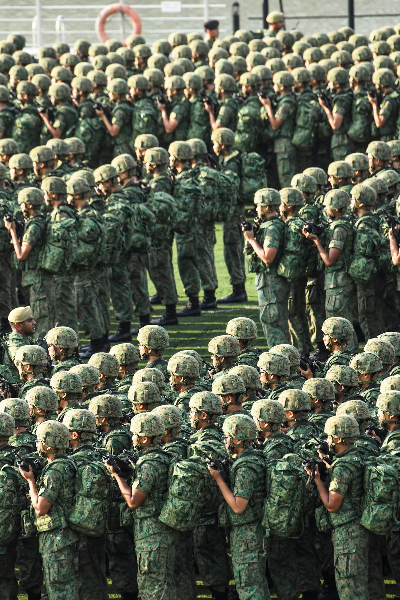 A large group of soldiers in camouflage uniforms, lined up and holding weapons, likely during a military event or parade.