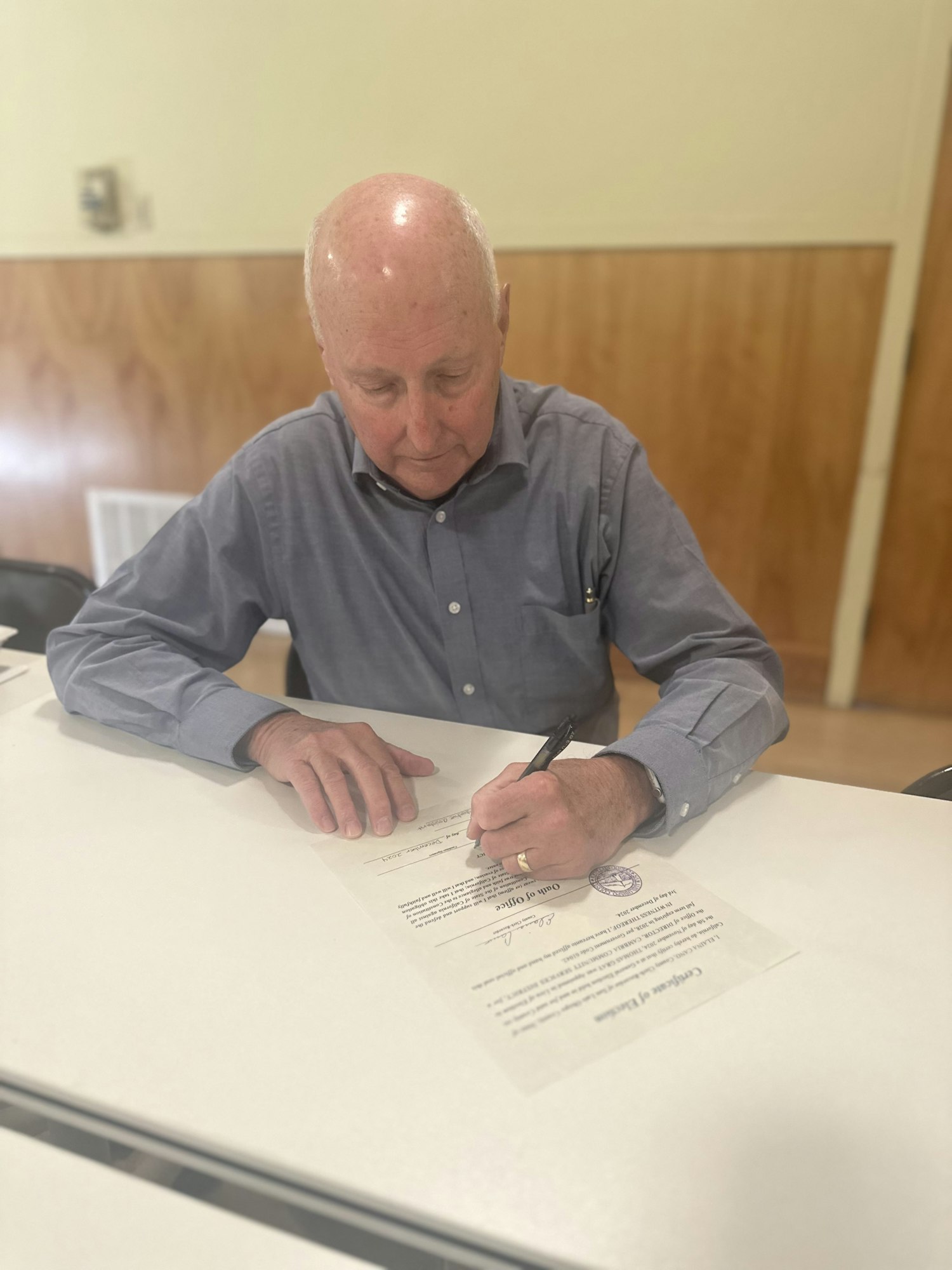 A person is sitting at a table signing a certificate.