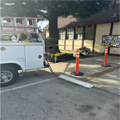 A utility truck with cones and caution tape, indicating some type of work or incident at the location.