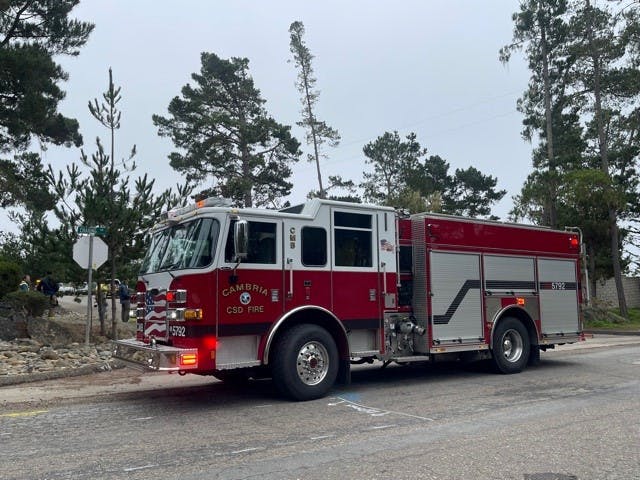 A red Cambria CSD fire truck parked on a road with trees in the background.