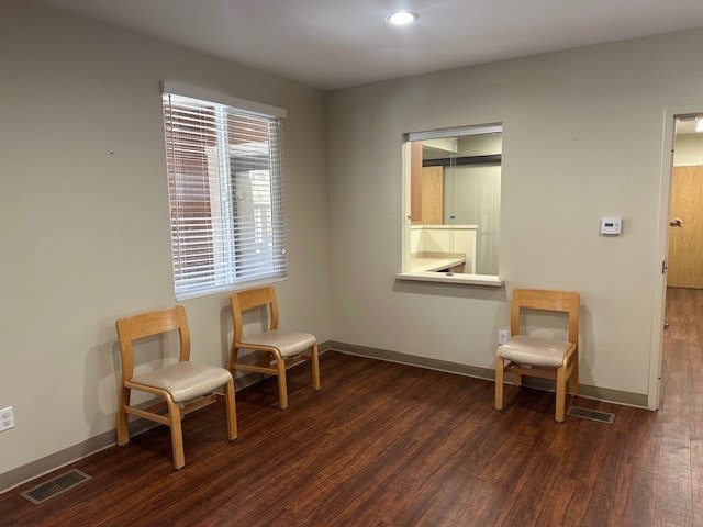 A room with chairs, a window with blinds, and a reception window.