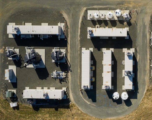 Aerial view of industrial buildings with HVAC units on rooftops, arranged in a semi-circular layout.