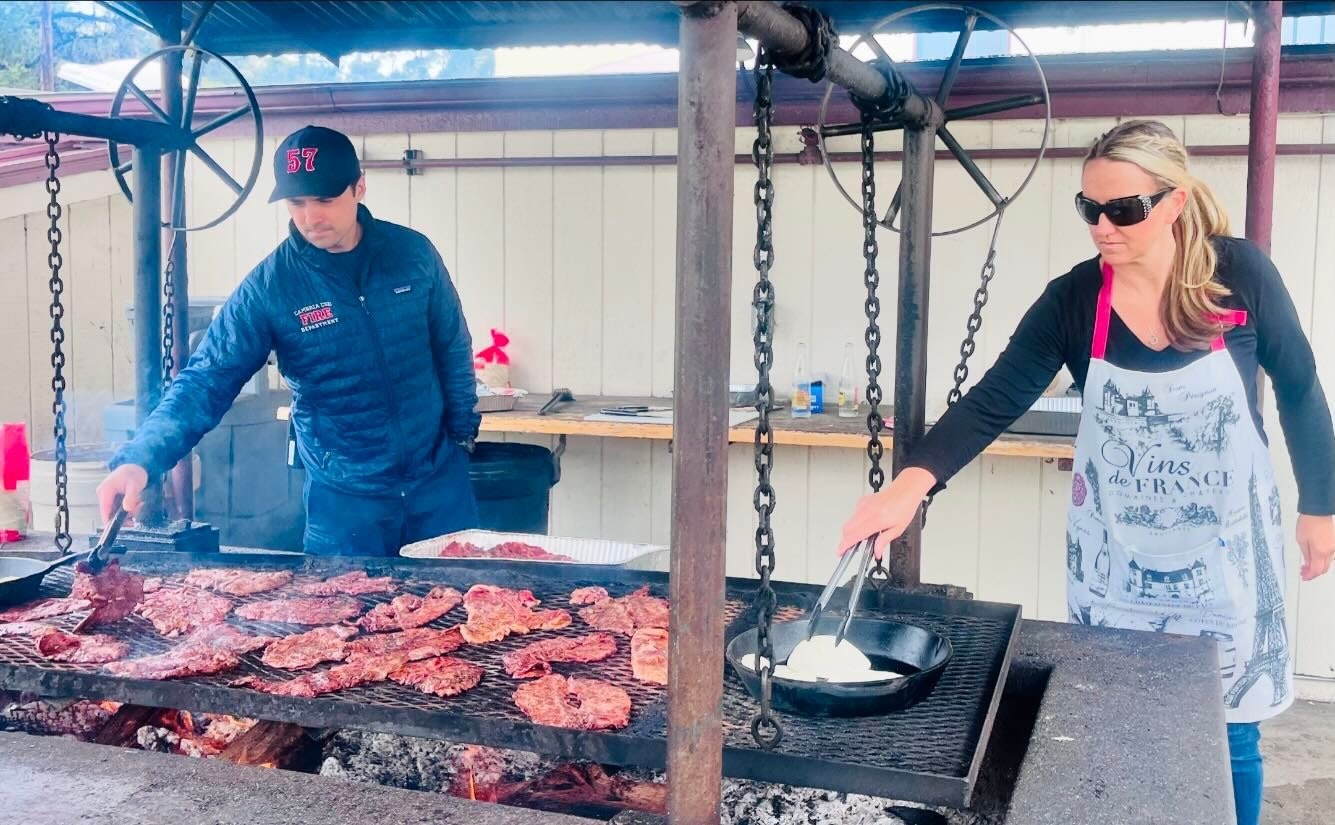 Two people grilling meat outdoors.