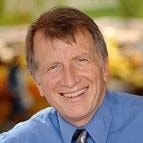 Older gentleman wearing a blue shirt and tie.