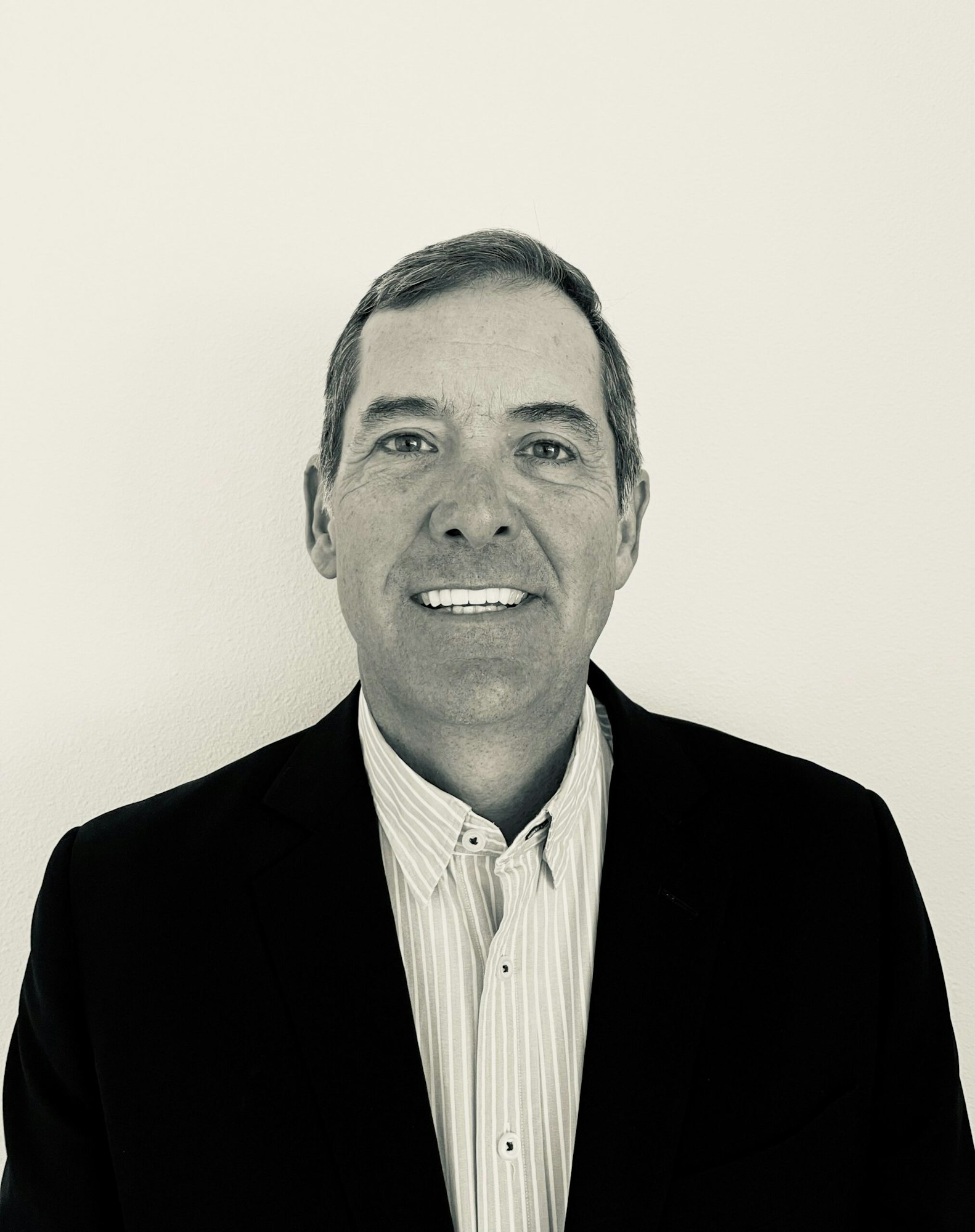 A black-and-white portrait of a man in a suit, smiling.