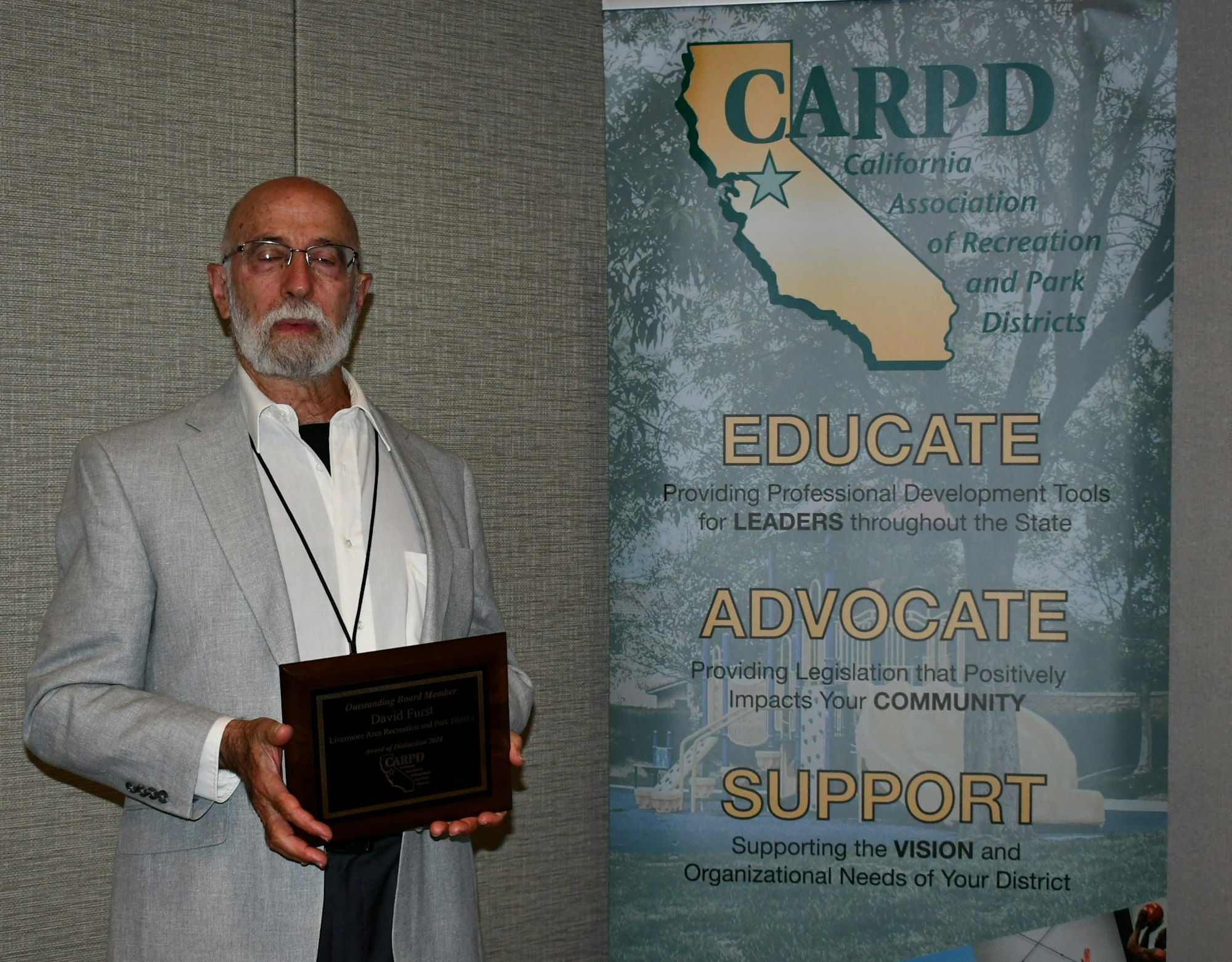 A man holding an award in front of a CARPD banner.