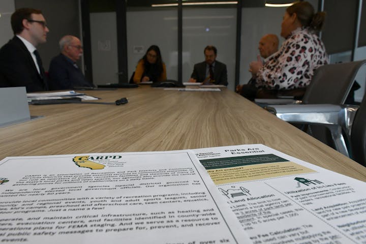 A group of people in a meeting discussing CARPD and parks, with documents on the table.