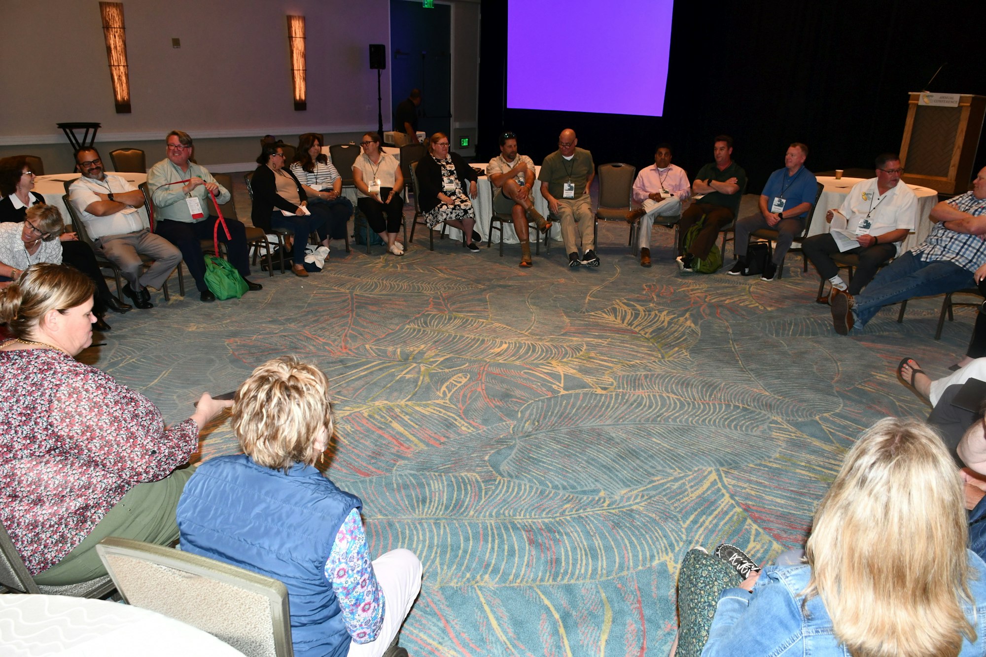 People sitting in a circle in a conference room, discussing or attending a workshop.