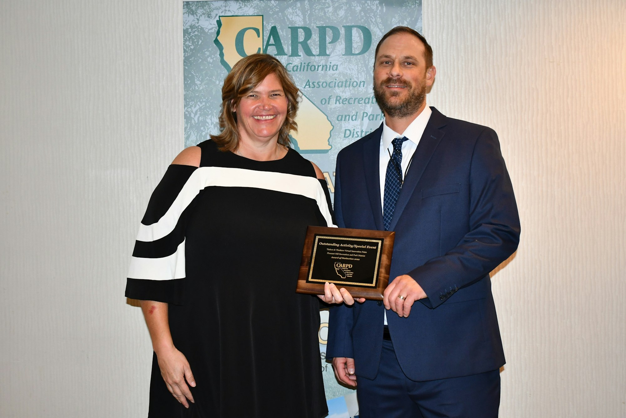 A woman and a man stand together, smiling, as he presents her with an award from the California Association of Recreation and Park Districts.