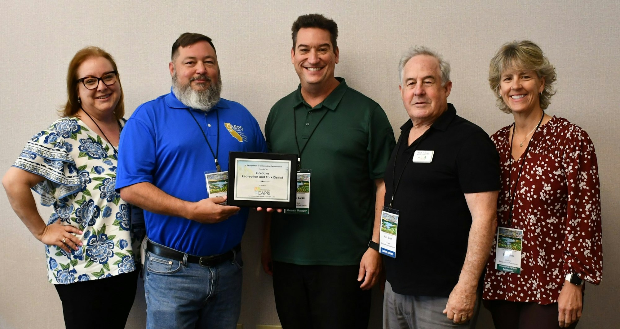 Five individuals posing with an award plaque.