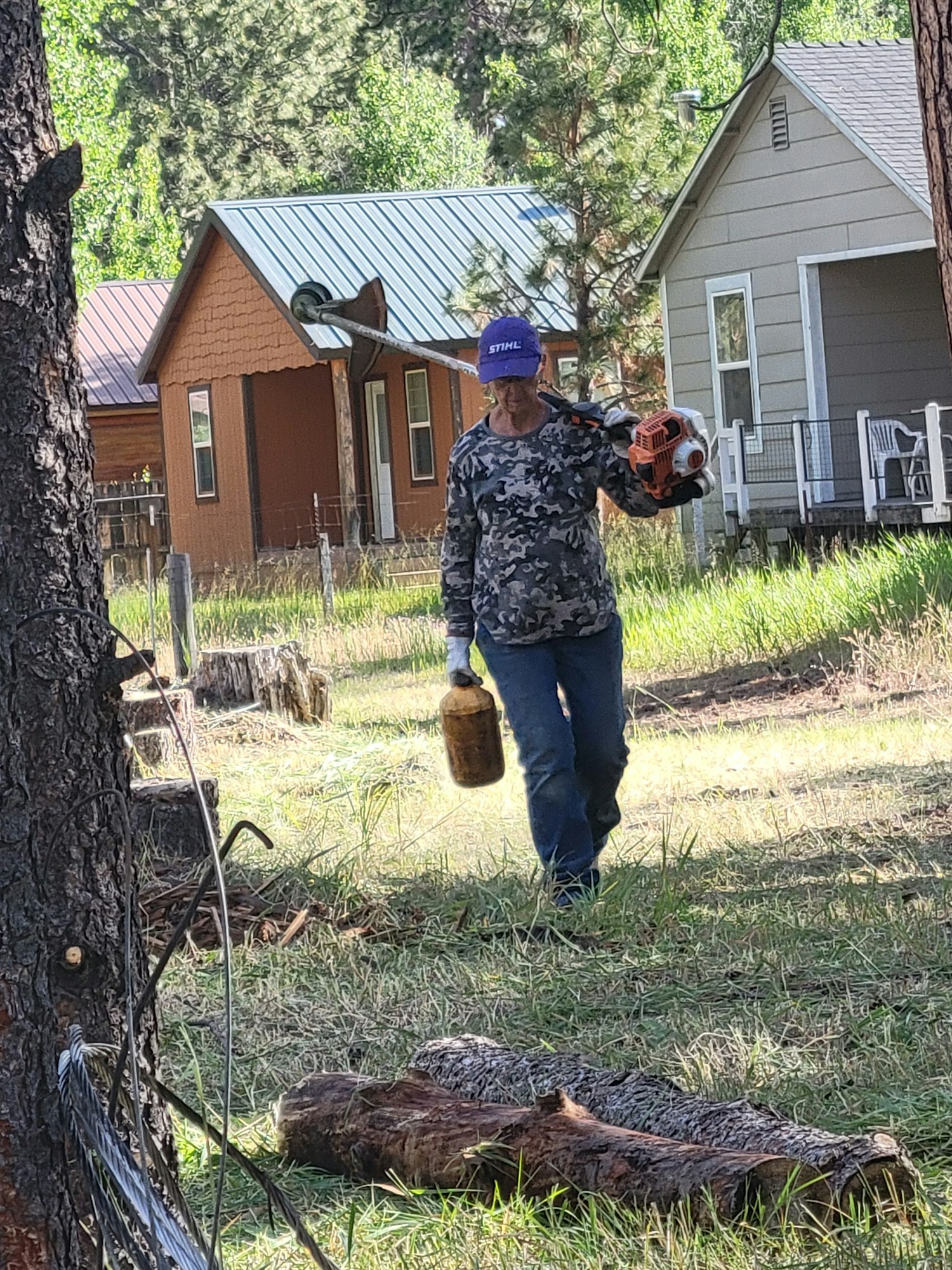 A person with a leaf blower, house in background, image rotated 90 degrees clockwise.
