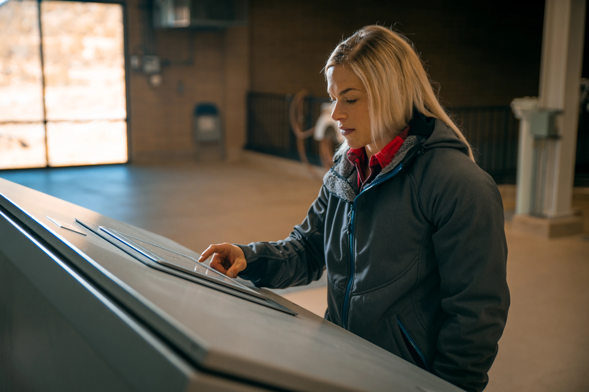 Woman examining a touchscreen display inside a building.