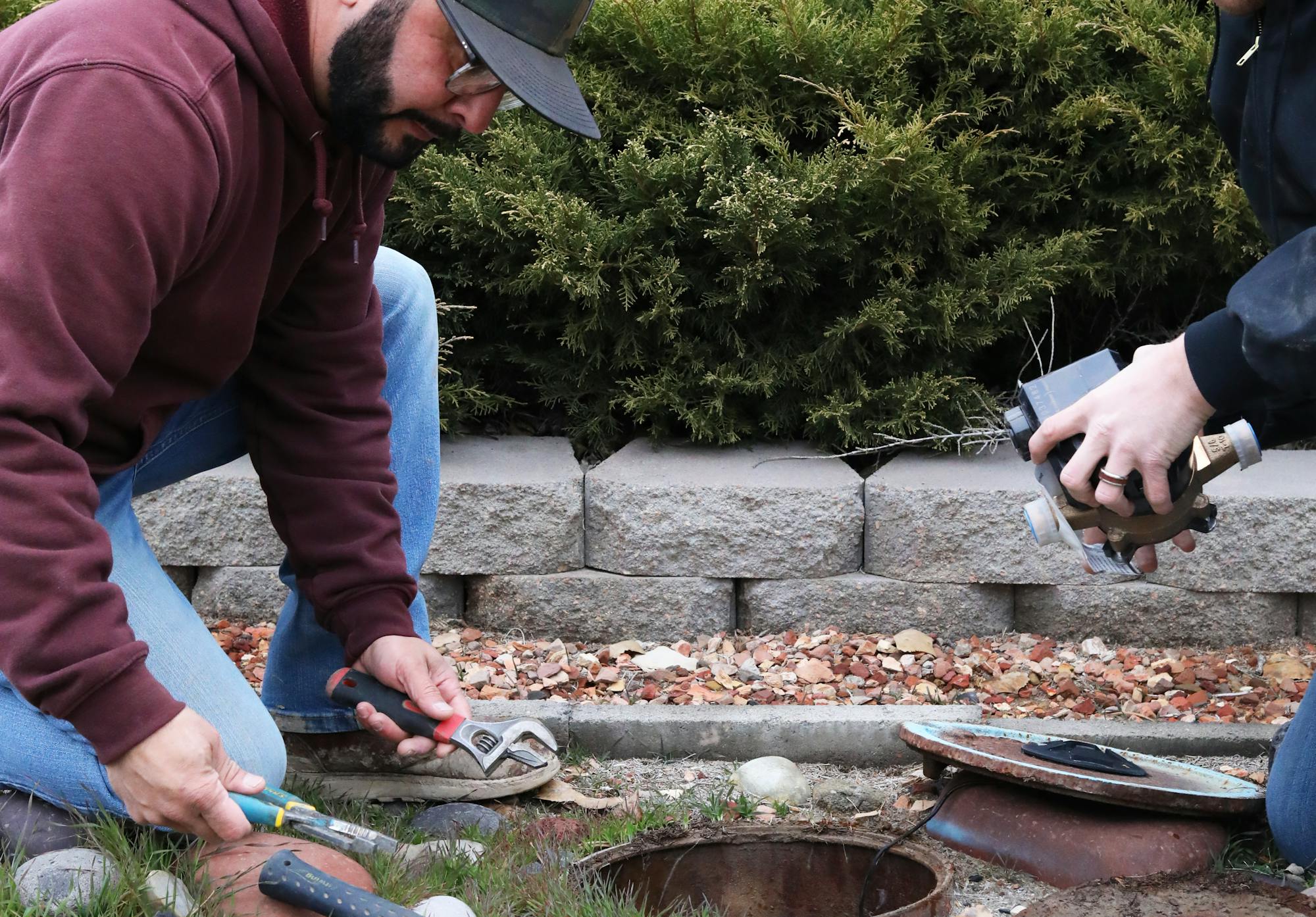 Two men making repairs to a water meter