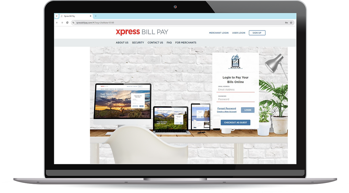 A laptop showing a bill payment website on its screen, placed on a desk against a brick wall backdrop.