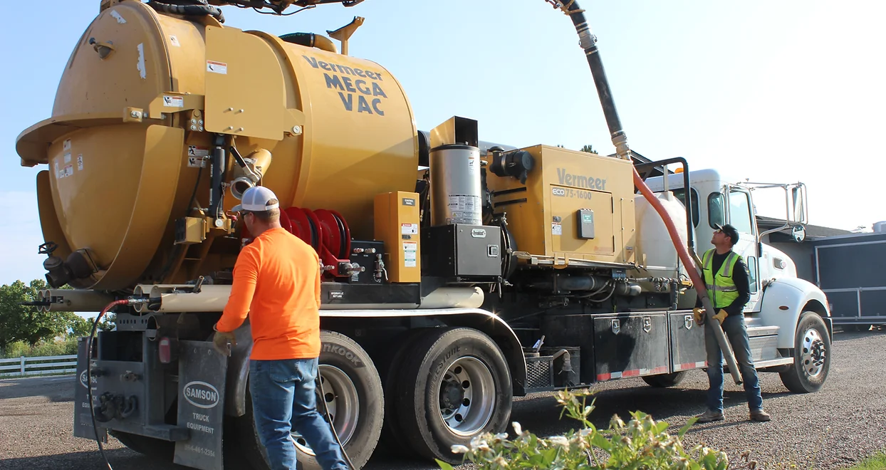 Two workers operating a Vermeer vacuum excavator truck.