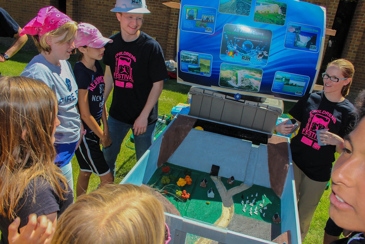 Group of people engaging with an educational water model display outdoors.