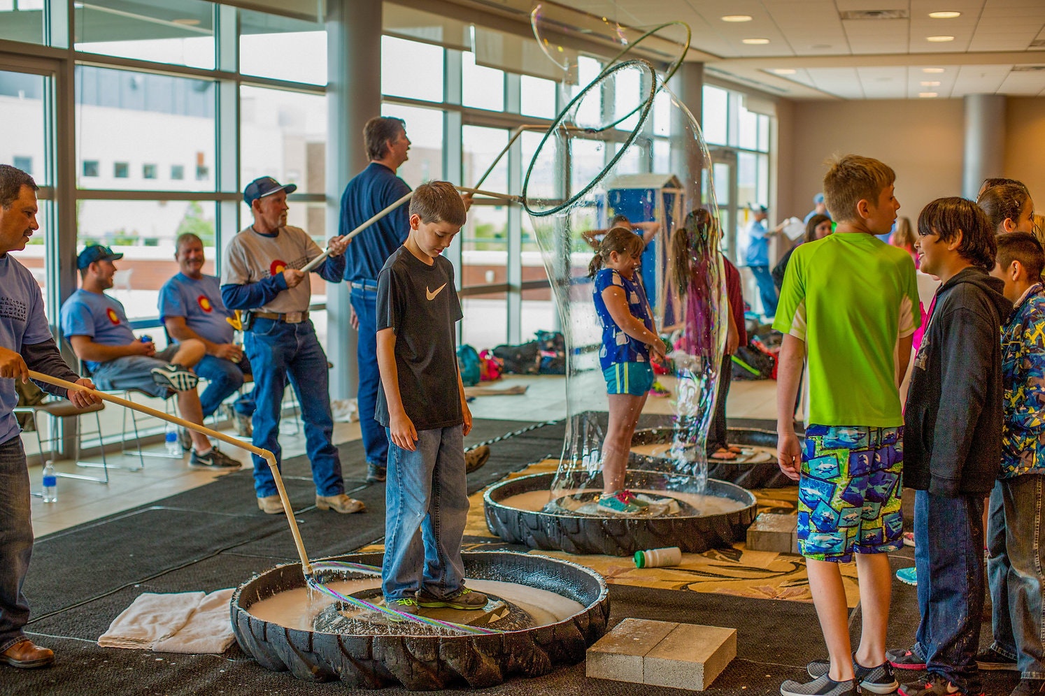 Kids and adults enjoying bubble making at an indoor event.