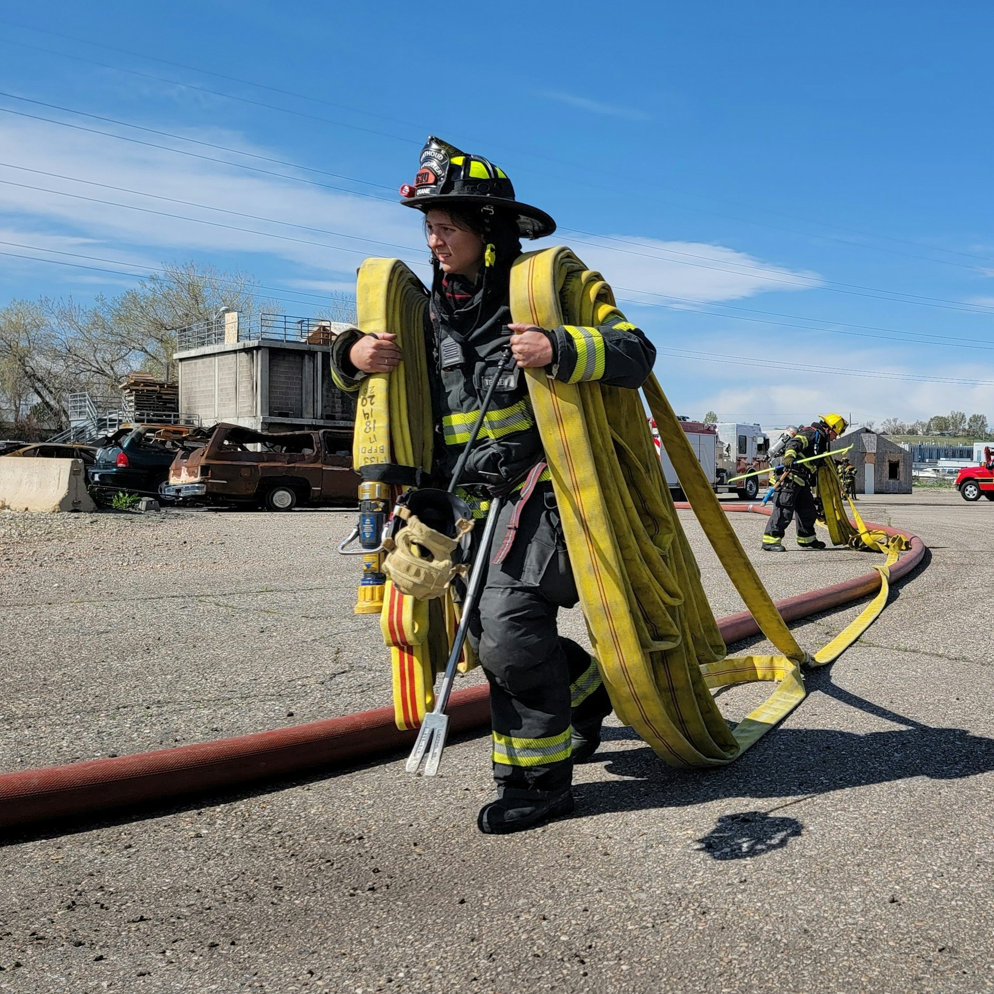 A firefighter carrying hoses during training.