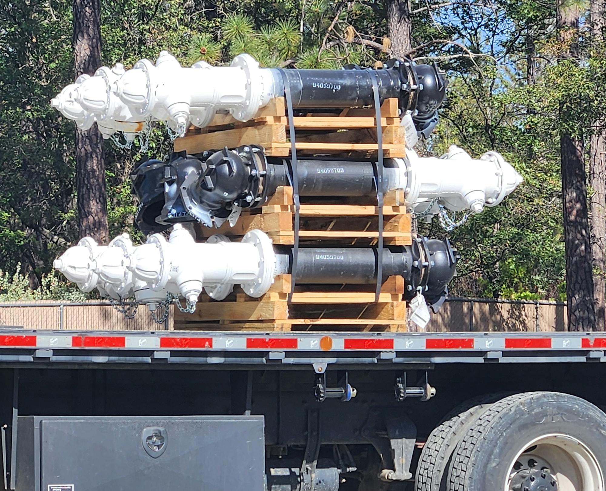 Fire hydrants stacked on a flatbed truck in a forested area.
