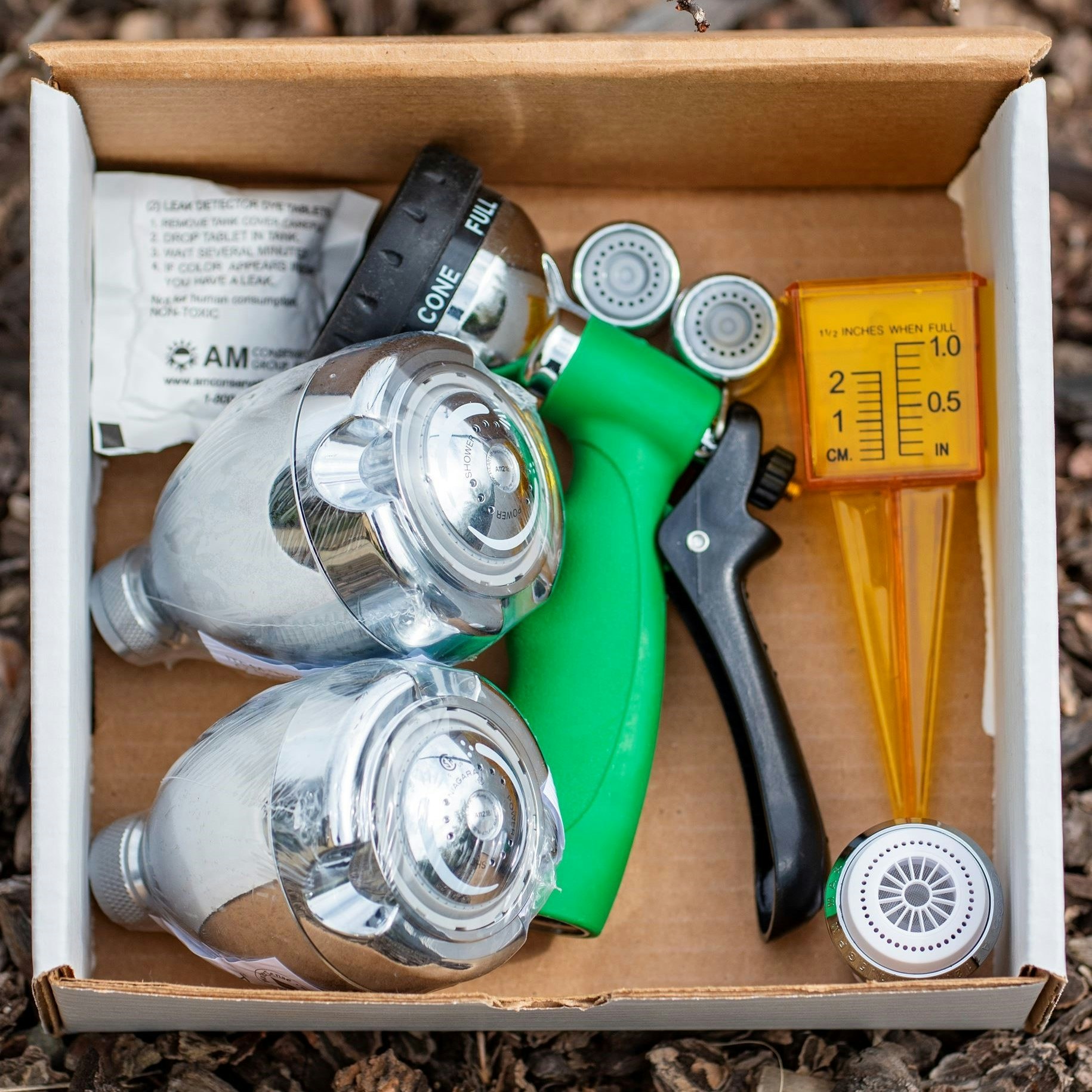 Garden hose nozzles, sprayer, and a rain gauge in a box.