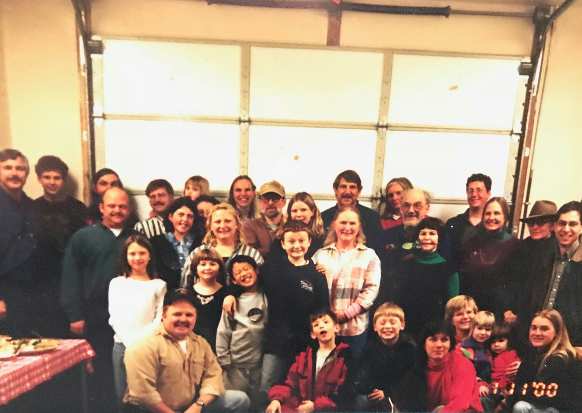 A large group of people, including children and adults, posing together in a garage, likely for a family gathering or event.