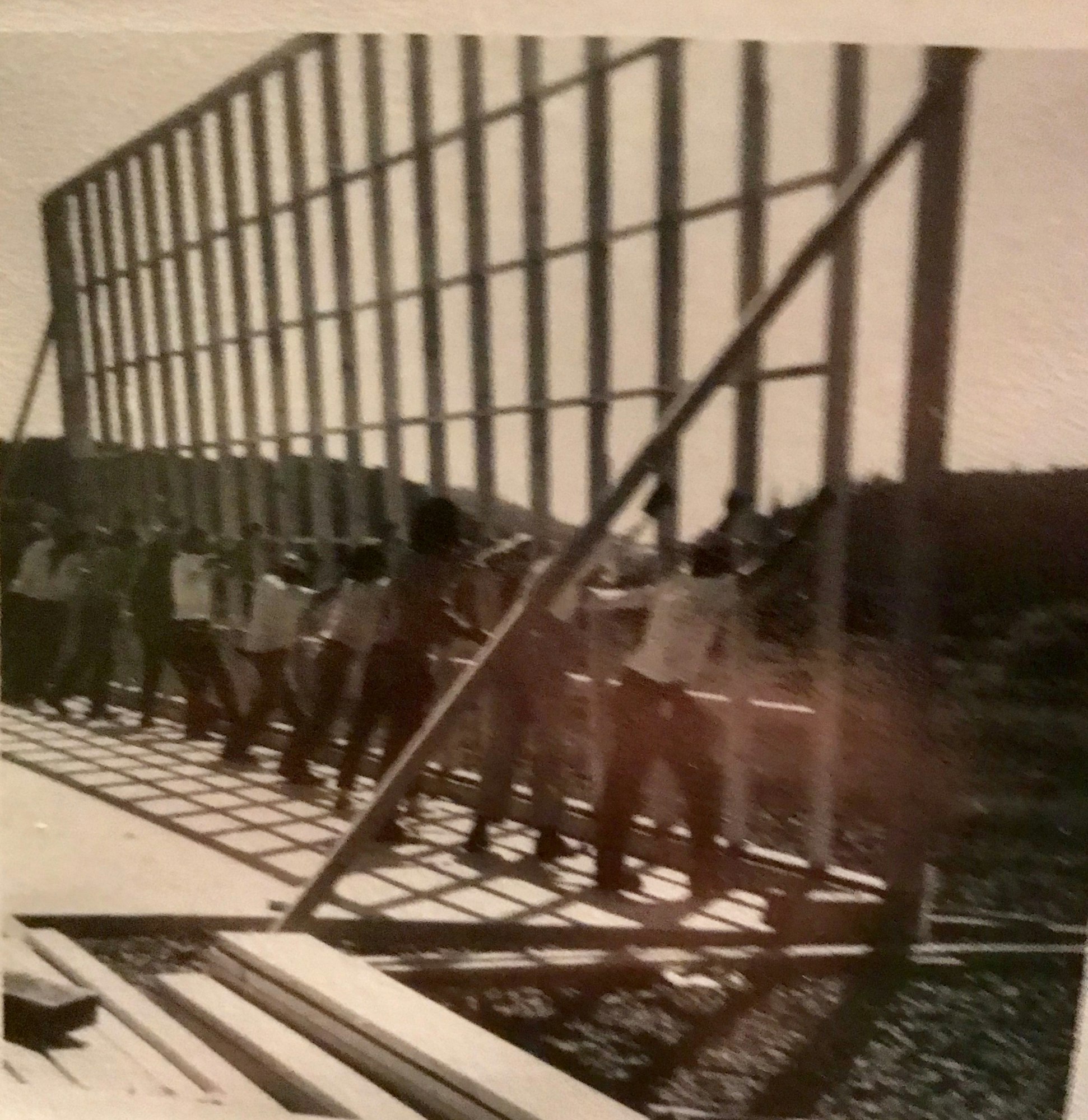 A group of people appears to be working together to lift or adjust a large frame structure outdoors.