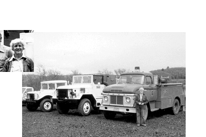 A black-and-white photo of several trucks with a person standing in front of them, possibly showcasing vintage vehicles.