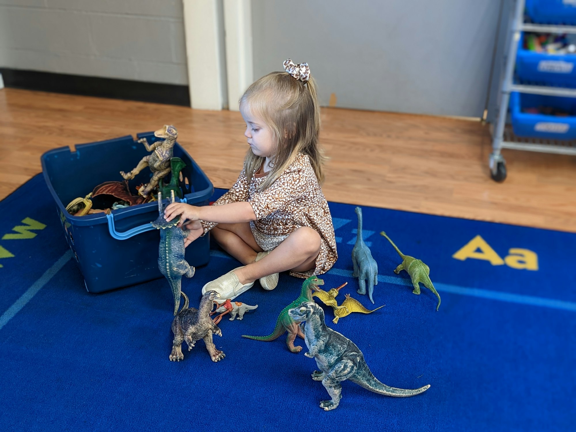 May contain: floor, flooring, wood, hardwood, child, female, girl, person, animal, dinosaur, reptile, face, head, photography, and portrait