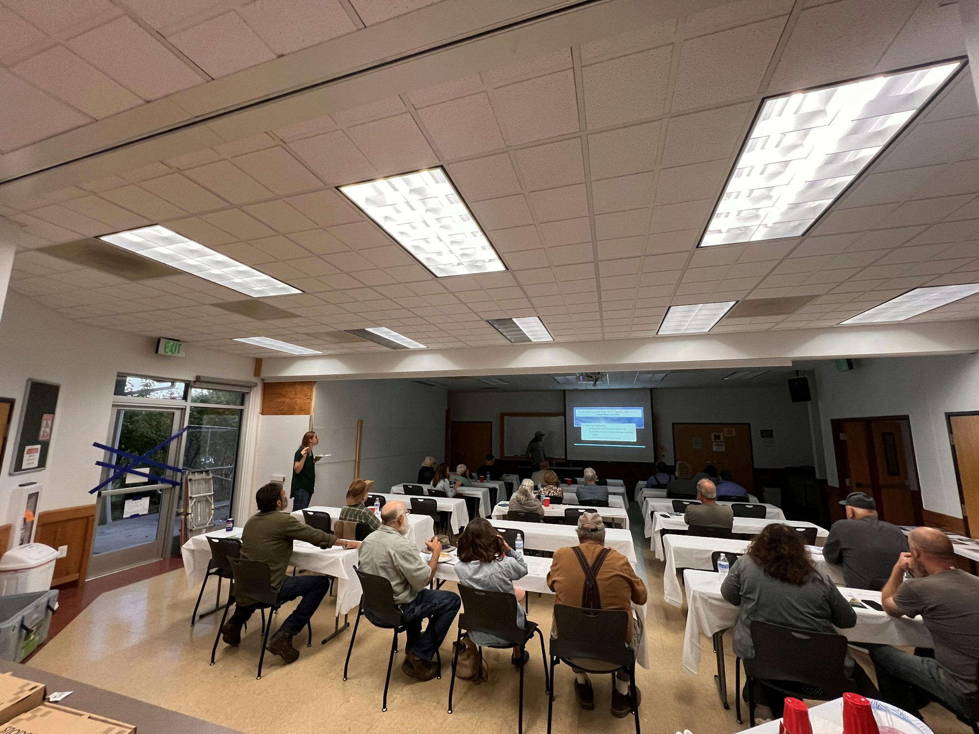 People seated in a room watching a presentation projected on a screen.
