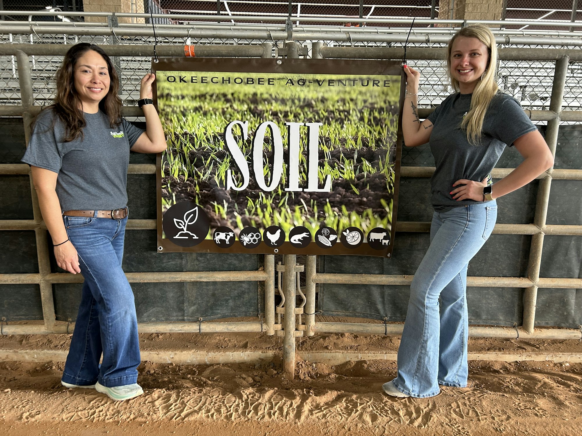 Two women stand next to a banner that says "SOIL," highlighting agricultural themes and Okeechobee's attractions.
