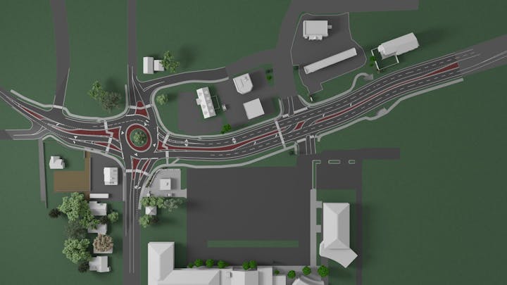 Aerial view of a roundabout with roads, buildings, and green spaces in an urban layout.