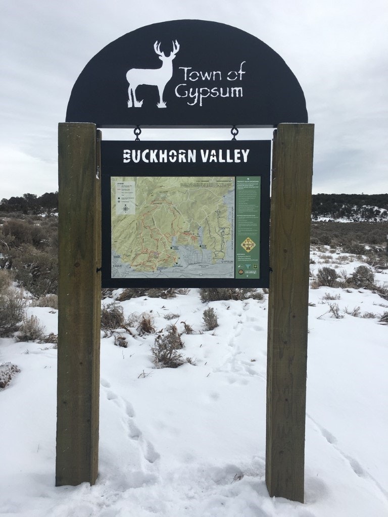 Sign for Town of Gypsum's Buckhorn Valley with a map, set in a snowy landscape.