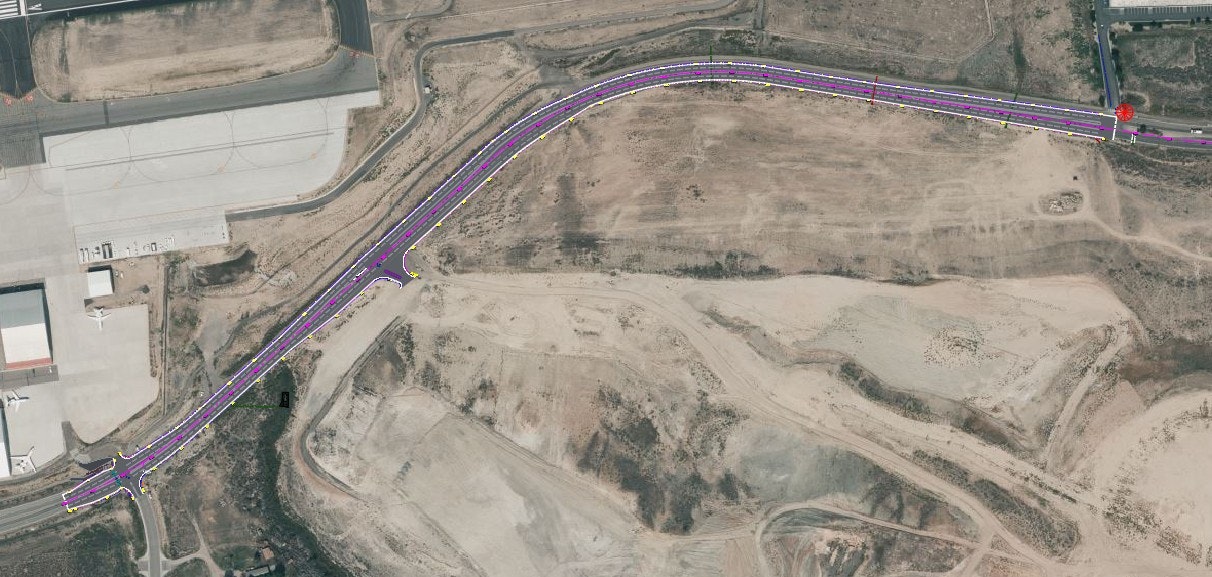 The image shows an aerial view of a winding road near an airport, with marked lanes and surrounding barren land.
