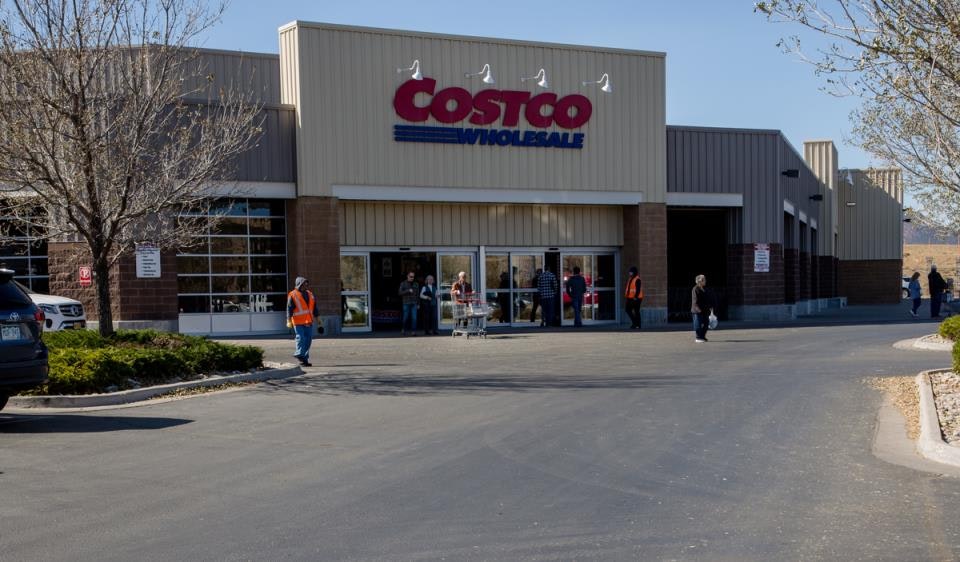 Costco wholesale store entrance with people and shopping carts outside.