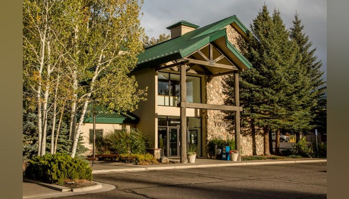 A building with a green roof, stone exterior, surrounded by trees and shrubs, and an entrance labeled "town."