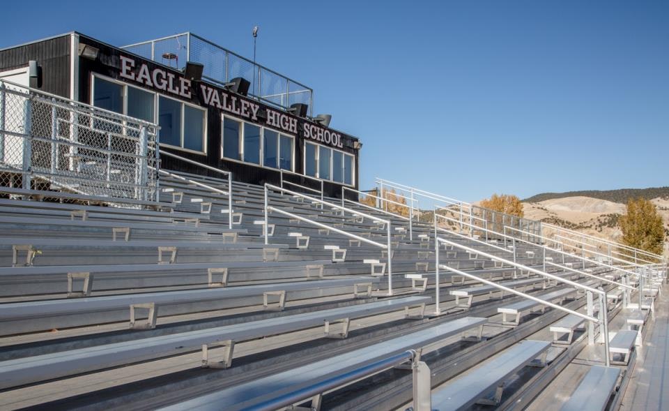 Empty metal bleachers at Eagle Valley High School with a sunny sky and hills in the background.