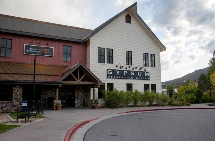 Building labeled "Gypsum Recreation Center" with stone and wood exterior, trees, and partly cloudy sky.