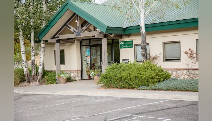 Building with green roof, labeled "Community Development," surrounded by trees and plants.