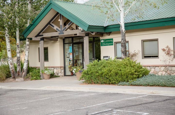 Building with green roof, labeled "Community Development," surrounded by trees and plants.