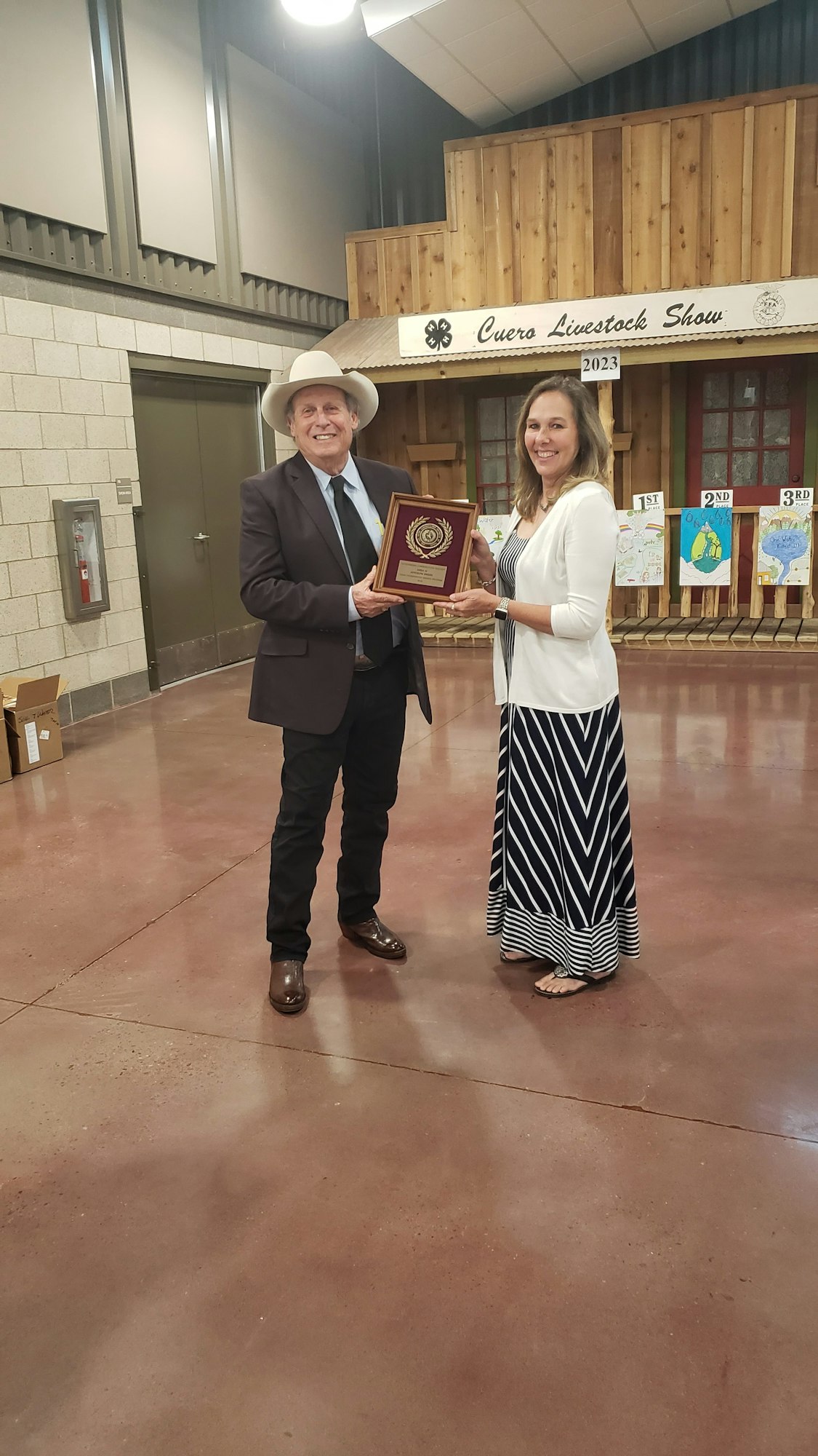 Two people holding a plaque at the Cuero Livestock Show in 2023.