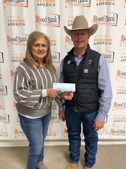 Two people standing together, one holding a check, in front of a Food Bank/Feeding America backdrop.