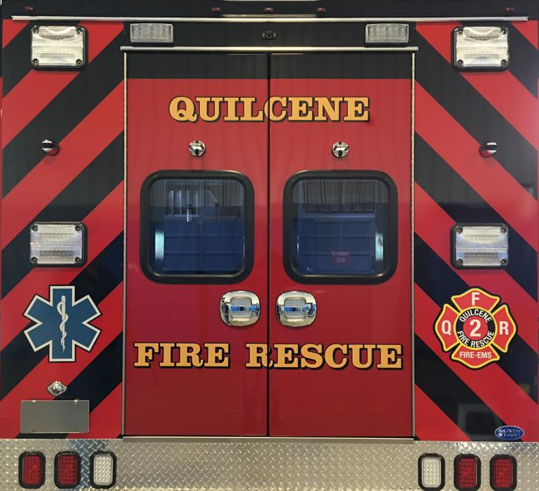 The back of a "Quilcene Fire Rescue" vehicle with lights and reflective stripes.