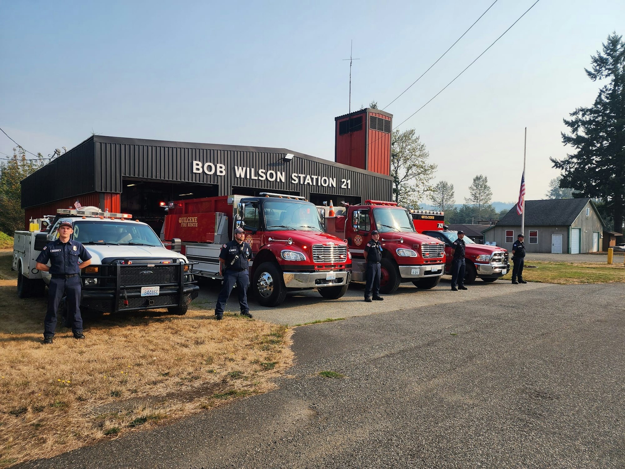 Firefighters and apparatus lined up in front of a fire station
