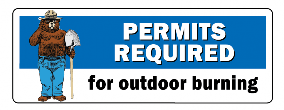 Sign saying "PERMITS REQUIRED for outdoor burning" with a cartoon bear wearing a hat and holding a shovel.